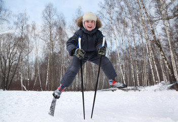 Fototapeta na wymiar Young boy jumps and spreads legs on cross-country skis