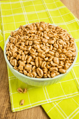 Sweet popped wheat grains in bowl on wooden background