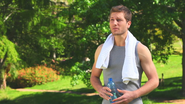 Dark haired man with a bottle of water and towel