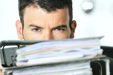 busy man hiding behind a stack of files