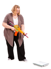 junge dicke Frau, die eine Waage bek&auml;mpfen will