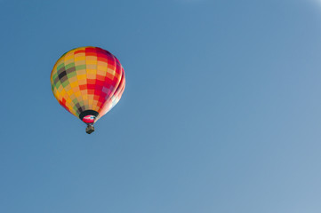 Hot air balloon rising serenely into an early morning blue sky.