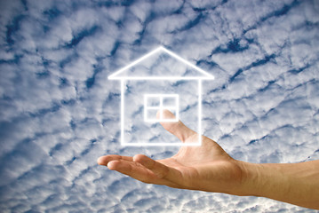 Fototapeta na wymiar House icon in the hand with cloudy sky background