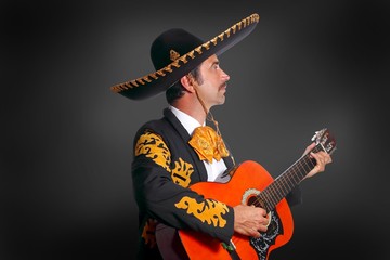 Charro Mariachi playing guitar on black