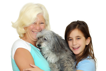 Grandmother and girl hugging the family dog on  white