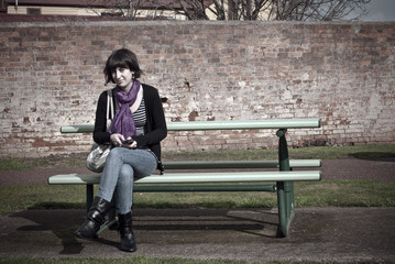 Young woman on park bench.  Edgy processing.