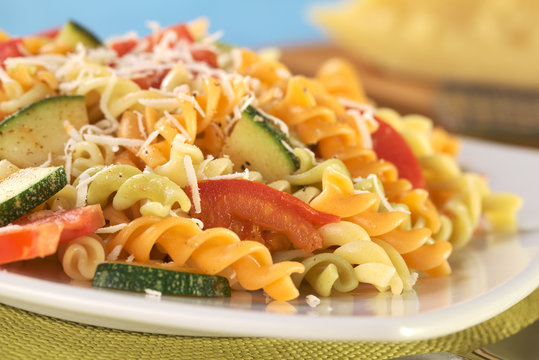Colorful fusilli pasta with zucchini, tomato and grated cheese
