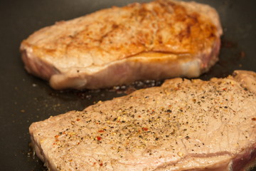Seasoned Strip Steaks Sizzling in a Pan