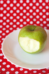 Green apple on a white plate on a red background