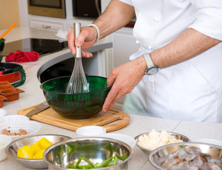 professional chef hands with kitchen utensils whisk and pan