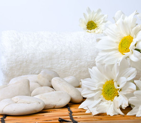 Fototapeta na wymiar The flower , a white towel and stones are on the bamboo mat. All