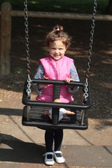 bambina che spinge una bambola sull'altalena