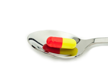 red and yellow tablet in spoon