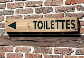 panneau indicateur toilettes sur fond de briques rouge