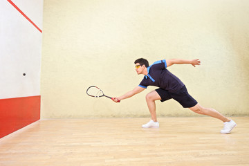 Squash player hitting a ball in a squash court
