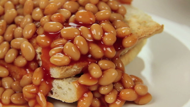 Hot baked beans poured and cascading over crisp toast.