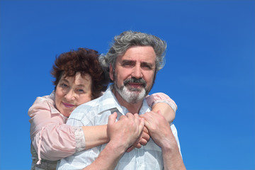 old woman embracing man from back, blue sky