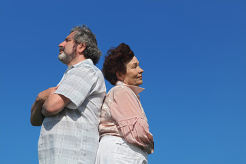 old woman and man standing back to back, crossed hands