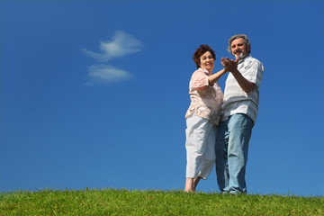 Fototapeta na wymiar old woman and man dancing on summer lawn, blue sky