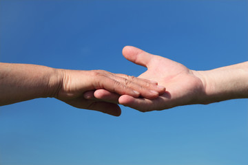 closeup of old people holding for hands, blue sky