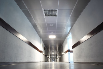 long gray hallway with doors, light at end of corridor