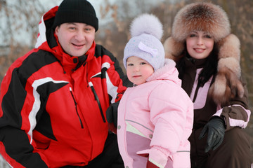 father, mother and little daughter at winter on nature