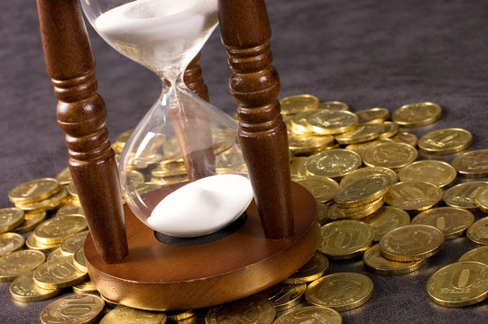 Hourglasses and coin On a grey