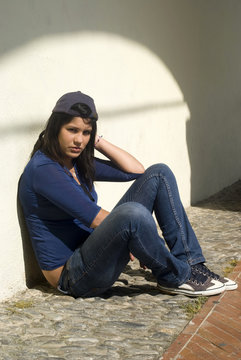 Sad girl sitting against a wall