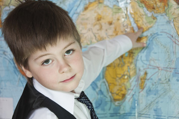 The boy is studying the physical map of the world