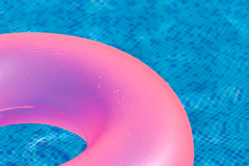 Floating pink ring on blue water swimpool.