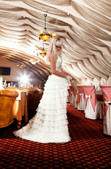 Beautiful blond girl in a wedding dress posing at restaurant