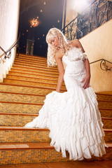 Beautiful girl in a wedding dress going down the stairs