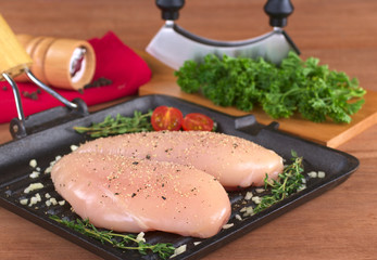 Raw chicken breast with seasoning in frying pan