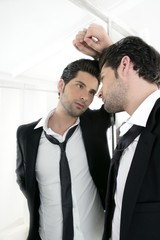 Handsome narcissistic young man looking in a mirror