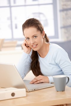 Young woman working on laptop in bright office