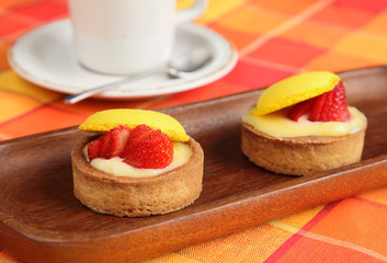 Strawberry pies and cup of coffee on orange table