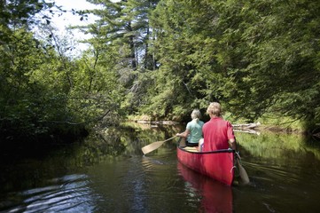 Muskokas, Ontario, Canada; Couple Canoeing Down A River
