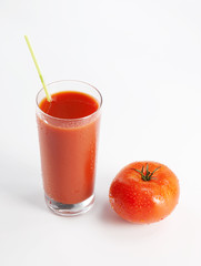 Fresh tomatoes and a glass full of tomato juice on white