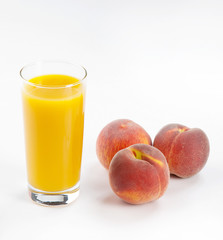 Glass with fresh peach juice near the peaches