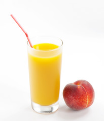 Glass with fresh peach juice near the peaches