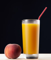 Fresh peach juce in glass on dark background