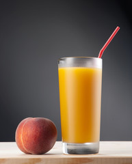 Fresh peach juce in glass on dark background