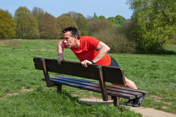 Fototapeta premium Runner doing pressups on a Park Bench