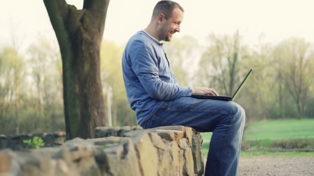 Young man chatting on laptop, outdoors