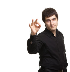 Portrait of young man in black shirt gesturing ok sign against w