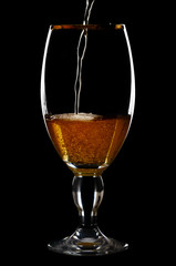 Beer into glass on a black