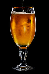 Beer into glass on a black