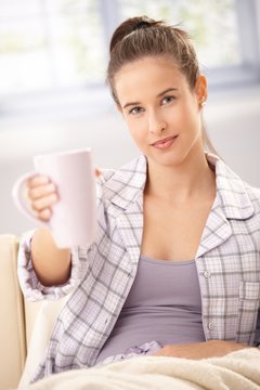 Woman in pyjama offering coffee