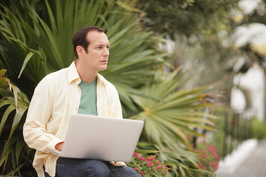 Image Of A Man Looking Away From His Notebook Computer