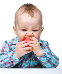 Little child is eating red apple